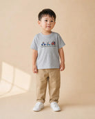 Young child wearing the grey Superheroes Save the Day kids T-shirt with beige trousers