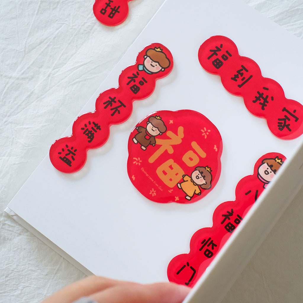 Festive Chinese New Year couplet magnets with red blessings and cute character designs, displayed on a white surface.