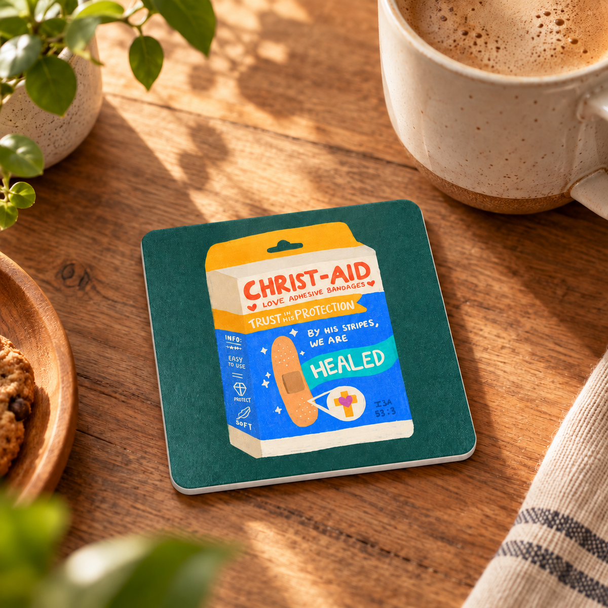 Christ-aid Love Bandages Christian coaster styled on a warm wooden table with coffee