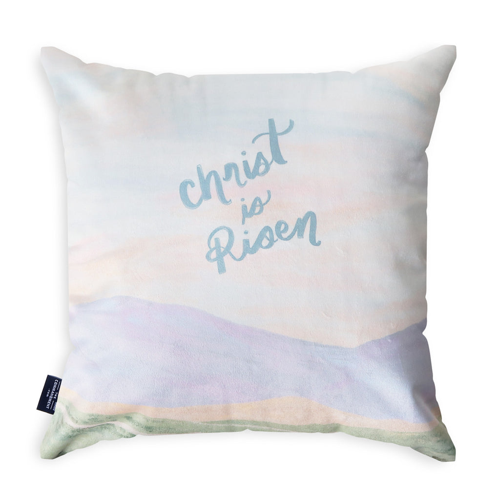 Decorative throw pillow featuring the text 'Christ is Risen,' designed with soft pastel tones, perfect for Easter and Christian faith-based home decor.