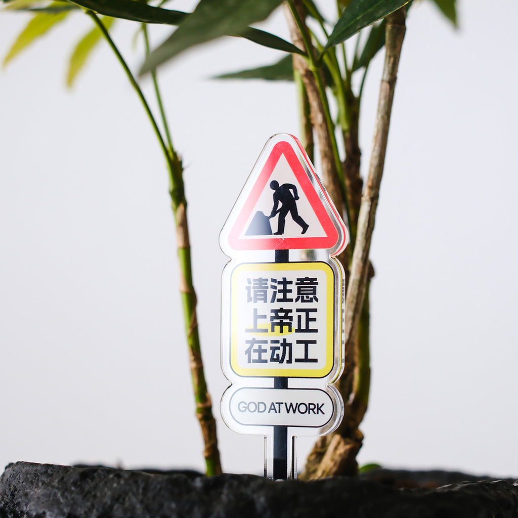 A Christian acrylic desk sign with the message 'God at Work' displayed in a plant pot, combining faith-inspired decoration with a meaningful message.