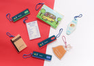 Christian acrylic keychains styled on an open notebook, featuring Jesus Loves You card, Abba Store receipt, and God’s Love Is Extra Gao drink bag designs