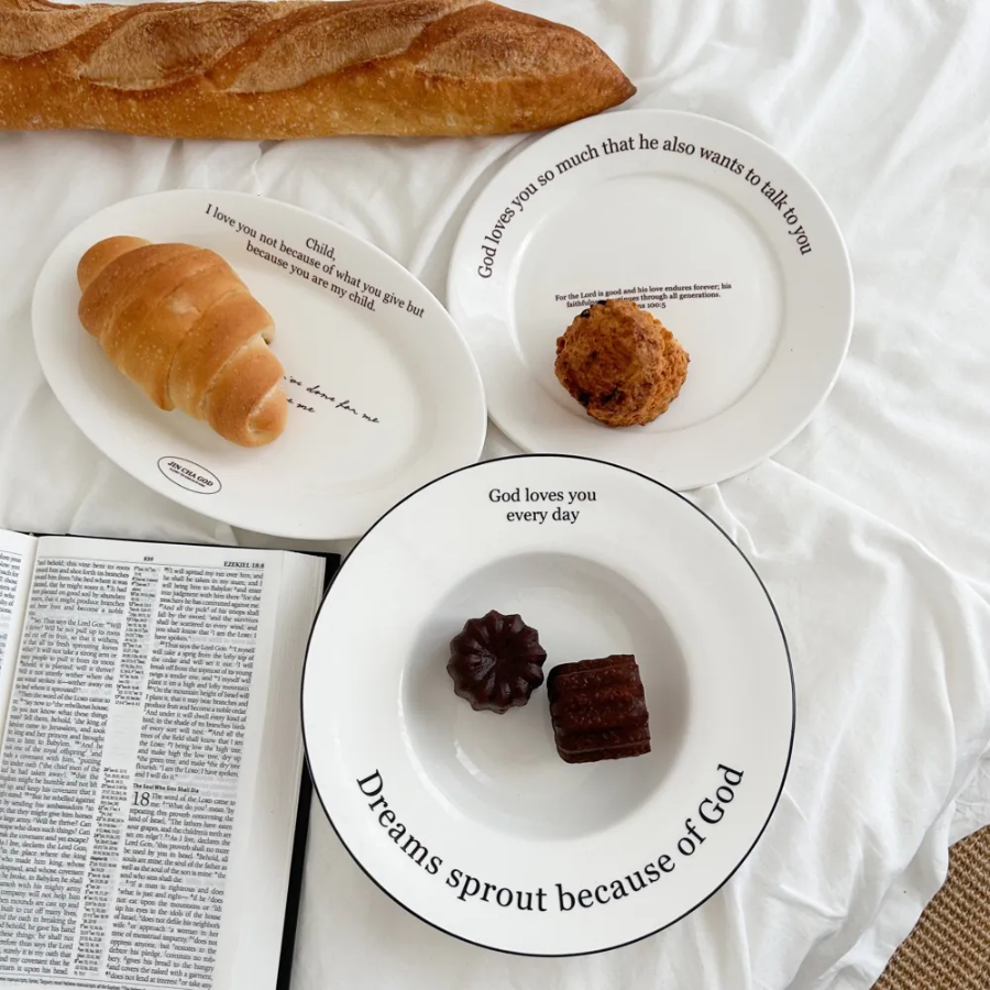 Inspirational Christian breakfast scene with bread, pastries, and scripture plates featuring uplifting messages like "Dreams sprout because of God," reflecting faith and simple happiness.