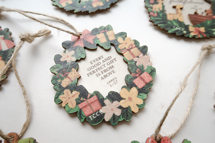 Close-up of a Christian Christmas wreath ornament with the Bible verse James 1:17, decorated with flowers and gift boxes