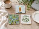 Christian coaster set featuring The Good Fruit, Wisdom Is Like Honey, and The Lord Is My Shepherd designs styled on a wooden table with a mug, Bible, greenery, and plate.