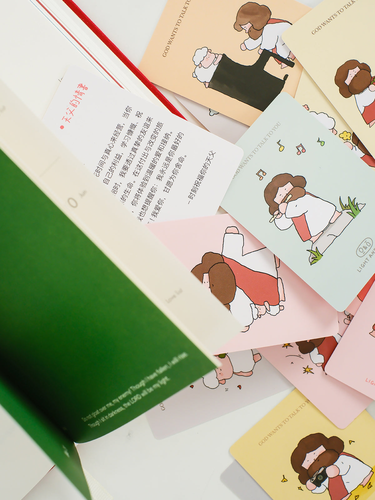 Christian mini encouragement cards beside an open book showing illustrated Jesus designs and faith-based messages in soft pastel tones