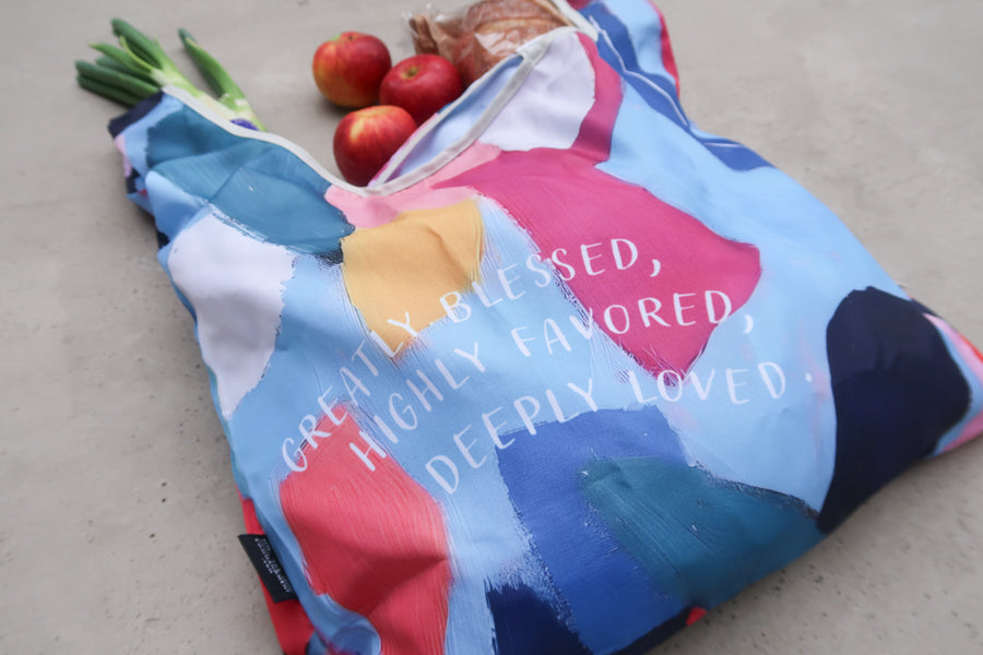 Close-up of Bible verse 
shopping bag with abstract 
colorful design and the 
words "Greatly Blessed, 
Highly Favored, Deeply 
Loved," a thoughtful 
Christian gift.