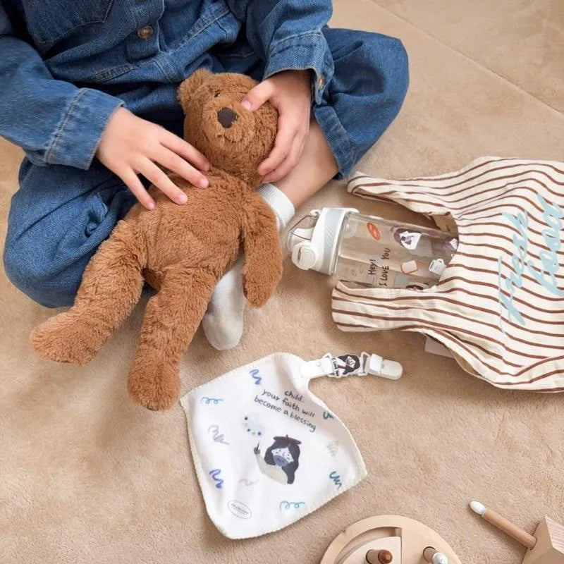Christian children’s handkerchief with a Jesus illustration and faith message styled with a teddy bear, water bottle and tote bag