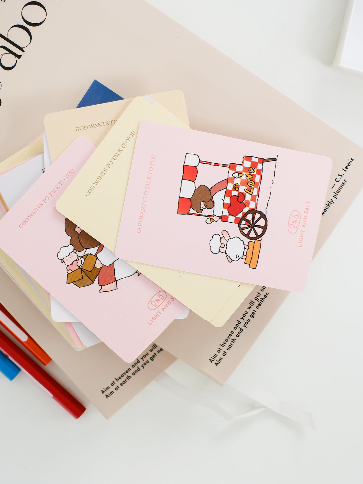 Stack of Christian mini cards with cute Jesus illustrations placed with stationery items, ideal as small faith-based gifts or encouragement notes