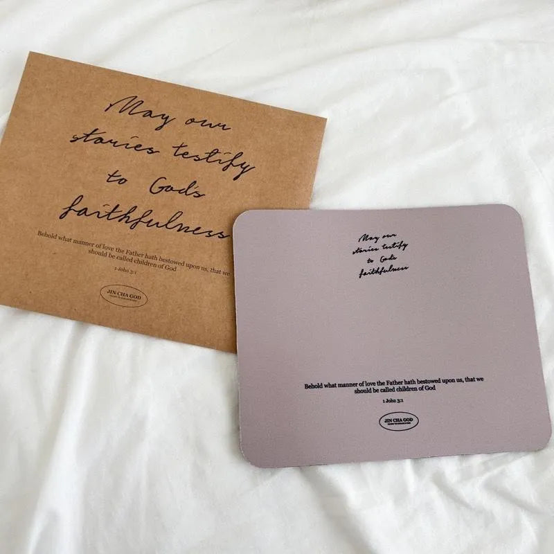 Christian mouse pad with the message “May our stories testify to God’s faithfulness” displayed beside its kraft envelope packaging