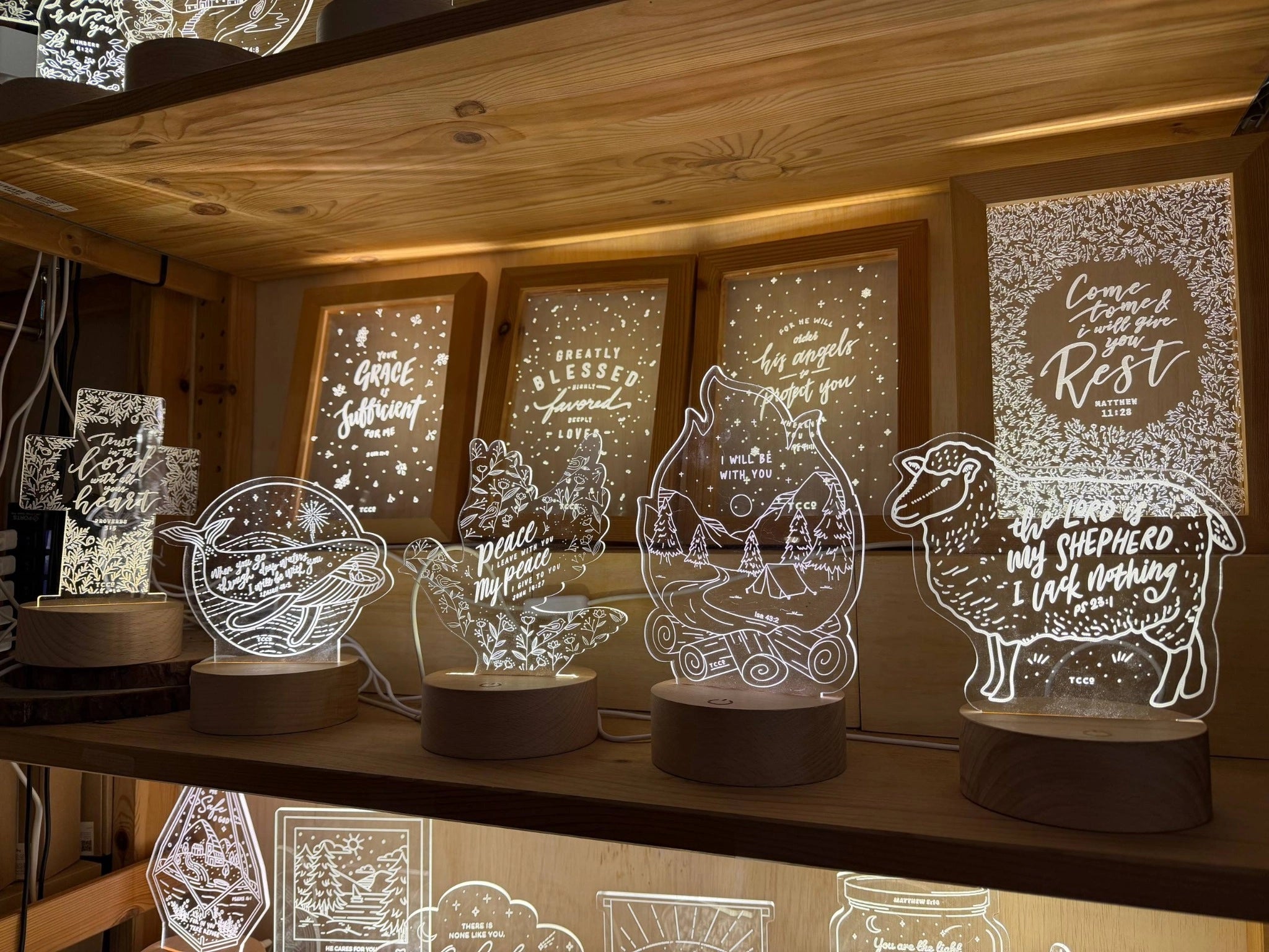 Glowing Christian night lights arranged on a wooden display shelf at The Commandment Co