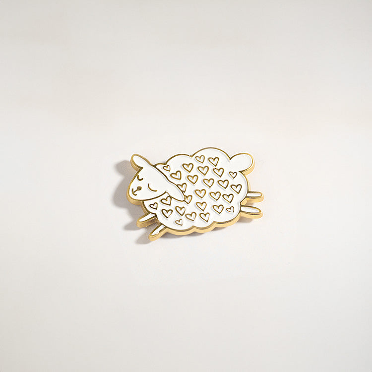 Cute enamel pin featuring a sleeping sheep with gold-plated edges and heart patterns on its wool. Inspired by Christian themes of faith and love, this sheep pin symbolizes being part of God's flock. Perfect as a Christian gift, Bible study accessory, or faith-inspired keepsake.
