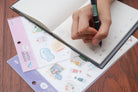 Hand placing a cute Christian sticker from everyday believer sticker sheet onto a planner, showing journaling and faith-inspired sticker use