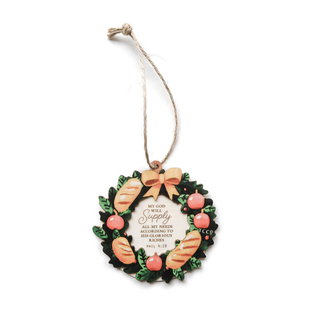 Christian Christmas ornament featuring a festive wreath with bread and apple designs, displaying the verse 'My God will supply all my needs' from Philippians 4:19, perfect for holiday decor or gifts.