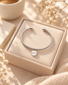 Believe circle pendant rope bracelet displayed on a cream jewellery box.