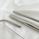Close-up of stainless steel straws engraved with the message "God loves you," showcasing the elegant design and included cleaning brush