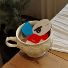 A decorative white bowl filled with colorful acrylic magnets featuring the words "Love," "Home," and "Grace," set on a wooden table with a soft cloth in the background.