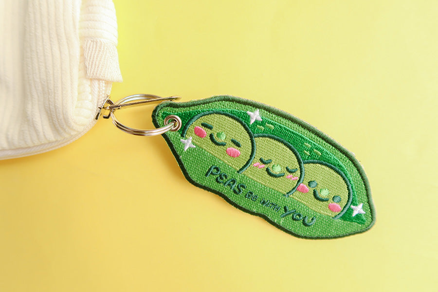 Keychain with 'Peas Be With You' embroidery and smiling peas.