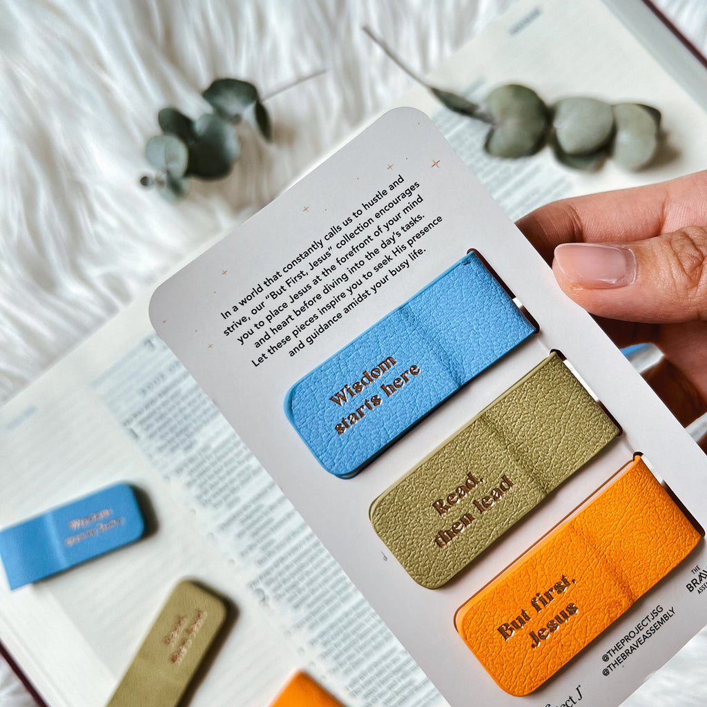 Colorful magnetic bookmarks labeled 'Wisdom starts here,' 'Reveal the need,' and 'But first, Jesus,' displayed over an open Bible with eucalyptus leaves in the background.