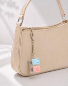 Command Love One Another double keycap keychain clipped to a beige handbag