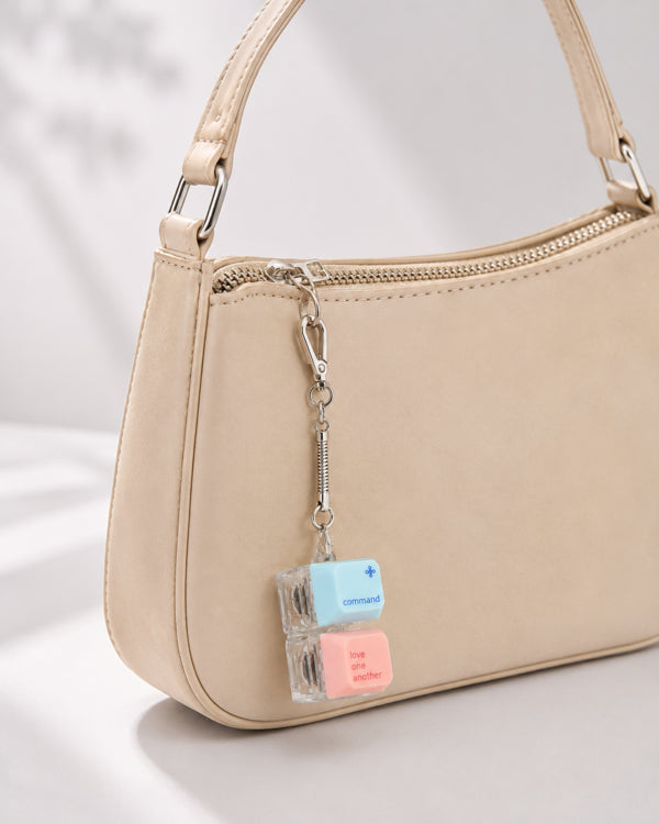 Command Love One Another double keycap keychain clipped to a beige handbag