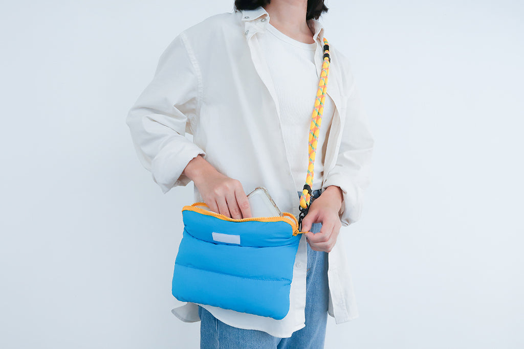 Model accessing the Cyan Pong Pong Bag, demonstrating its roomy interior and convenient padded design