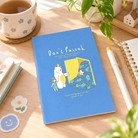 Don't Paiseh A5 Christian notebook styled on a bright wooden desk with coffee, greenery, stationery and warm morning light