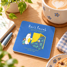 Don't Paiseh Christian coaster with white edge styled on a bright wooden table beside coffee and stationery.