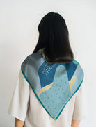 Back view of a model wearing a colorful abstract scarf featuring Ecclesiastes 3:1 “To everything there is a season” in a modern Christian design by The Commandment Co.