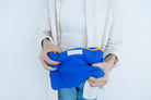 Hands squeezing the Electric Blue Pong Pong Bag, showcasing its lightweight and flexible design for easy portability
