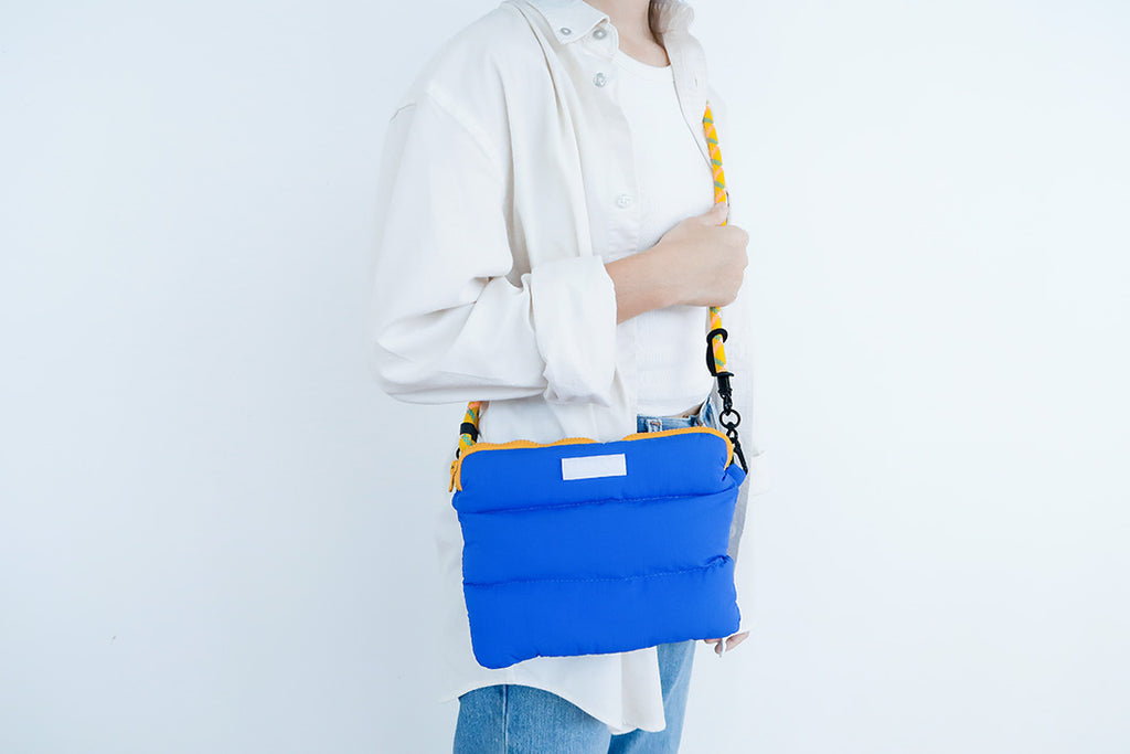 Person carrying the Electric Blue Pong Pong Bag with a durable strap, perfect for daily essentials and travel