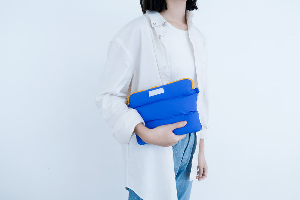 Person holding the Electric Blue Pong Pong Bag, featuring a soft padded texture and vibrant color contrast