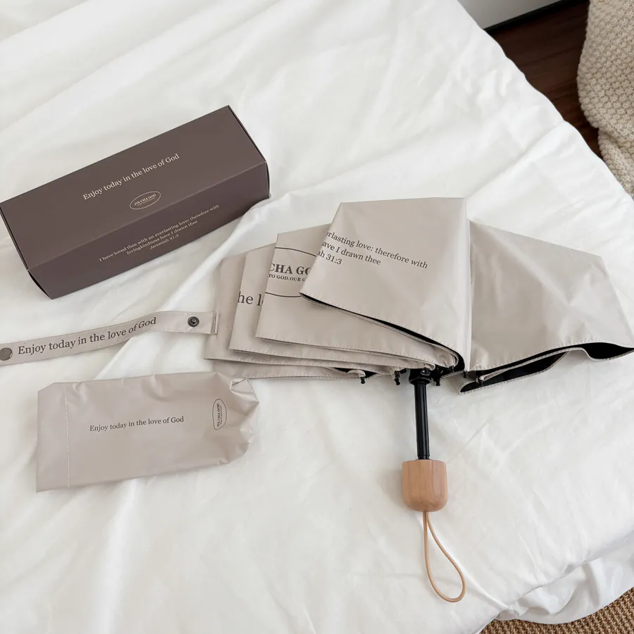 cream-colored Christian umbrella with “Enjoy today in the love of God” printed on the fabric, compact and elegant, perfect for daily use and faith-filled encouragement from The Commandment Co.