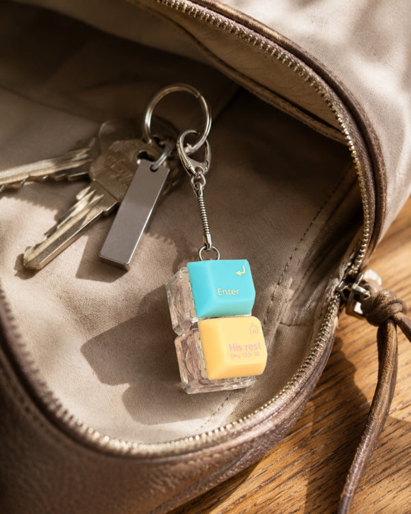 Enter His Rest double keycap keychain beside keys inside a brown bag