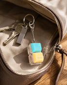 Enter His Rest double keycap keychain beside keys inside a brown bag