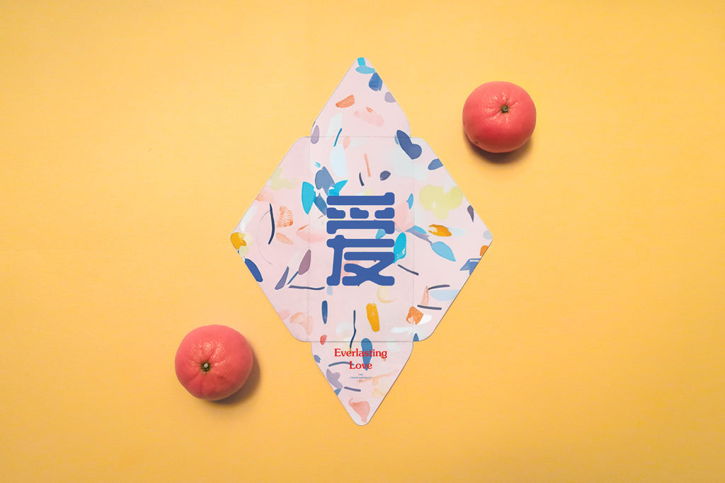 Chinese New Year red packet with 'Everlasting Love' theme, featuring pastel floral abstract patterns and a bold blue Chinese character, placed alongside tangerines on an orange background.