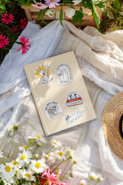 Journal decorated with Everyday Believer stickers featuring Christian messages like "Child of Light" and "Grace, Not Pressure," surrounded by flowers, from The Commandment Co, Singapore.
