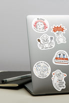 Laptop adorned with Everyday Believer stickers featuring Christian messages like "Rejoice," "Let God Cook," and "Not Luck, Just Faith," from The Commandment Co, Singapore.