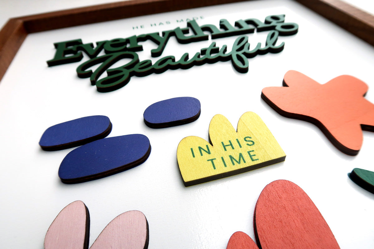 Close-up of a wooden scripture poster featuring the words "Everything Beautiful" and "In His Time" with colorful, handcrafted layered designs, perfect for inspirational and faith-based home decor.