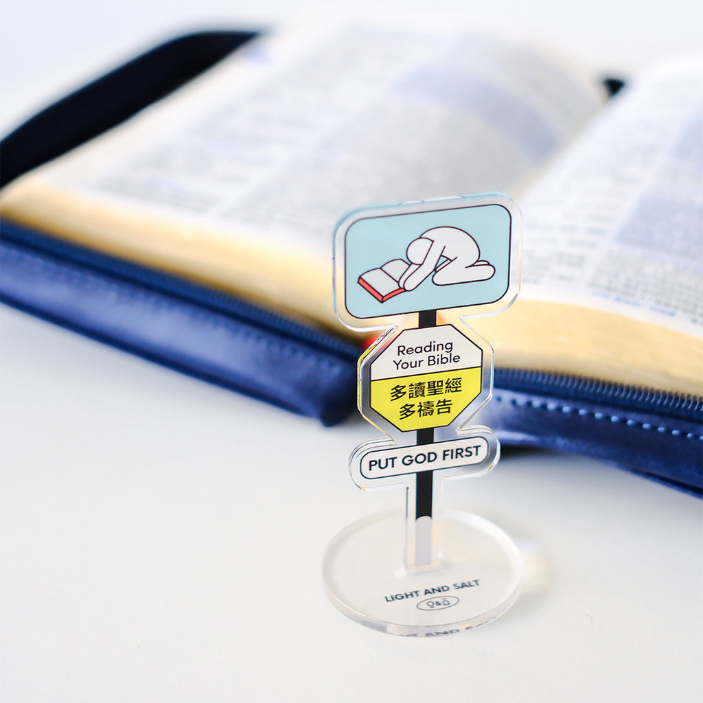 A Christian acrylic desk sign with the message 'Reading Your Bible' and 'Put God First,' displayed next to an open Bible, inspiring faith and devotion.