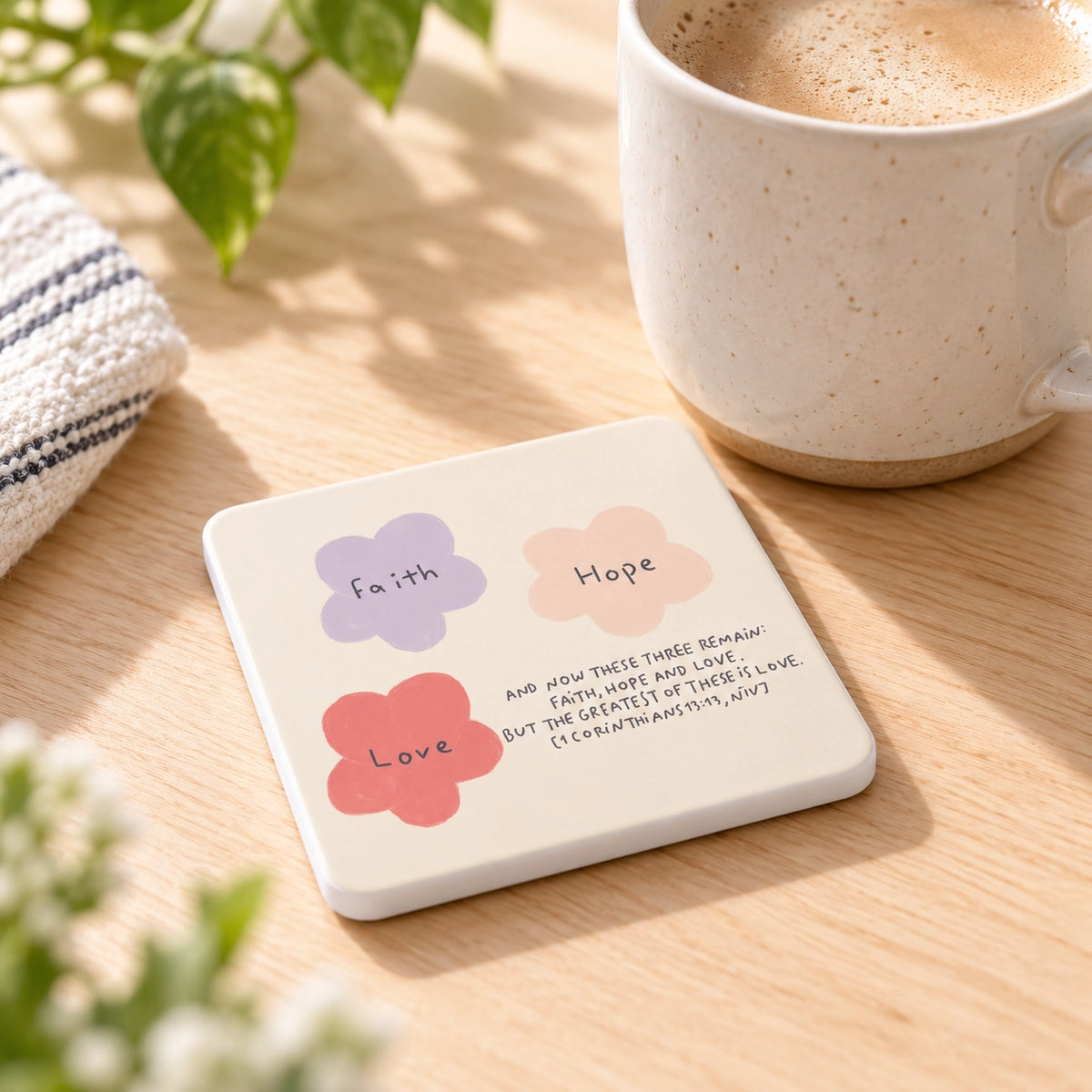 Faith Hope Love Christian coaster styled beside a ceramic coffee mug on a warm wooden table
