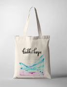 Christian tote bag with watercolor blue and pink waves and the words ‘Faith and Hope’, inspired by Romans 5:1–2 about peace with God through faith.