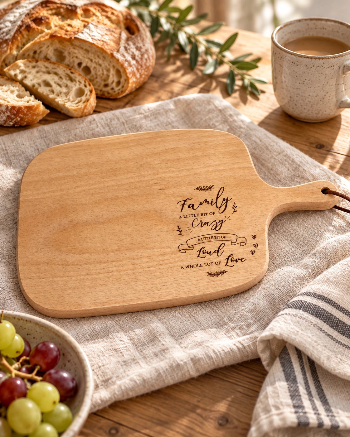 Family A Little Bit of Crazy wooden serving board styled with bread, grapes and a warm drink.
