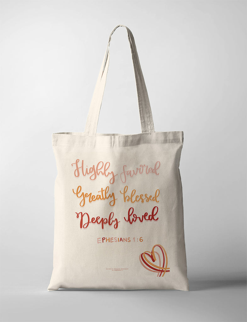 A beige tote bag featuring the inspirational quote "Highly favored, Greatly blessed, Deeply loved" from Ephesians 1:6, designed with elegant handwritten-style text in warm gradient tones and a heart illustration for a thoughtful and uplifting look.