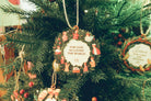 Beautiful 'For God So Loved the World' ornament featuring a Bible verse, hanging on a decorated Christmas tree with festive greenery.