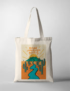 Christian canvas tote bag featuring “Behold I am doing a new thing” Bible verse with illustrated desert landscape, river, and sunrise, designed by Fouronetwo.sg in collaboration with The Commandment Co.