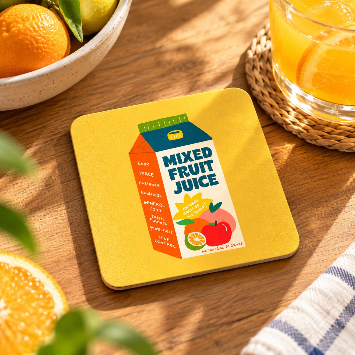 Fruit Juice of the Spirit Love Supermarket Christian coaster styled with fresh citrus fruit and orange juice on a wooden table.