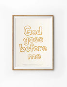 God Goes Before Me Christian poster with warm outlined typography in a wooden frame