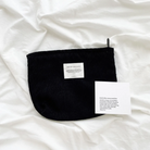 God is like warm sunshine black corduroy zipper clutch with an inspirational message patch, displayed on a soft white fabric alongside an encouragement card, reflecting simple happiness and faith.