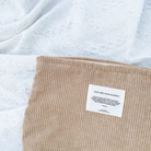 God is like warm sunshine brown corduroy zipper clutch with an inspirational message patch, placed on a textured white fabric, radiating simple happiness and encouragement.